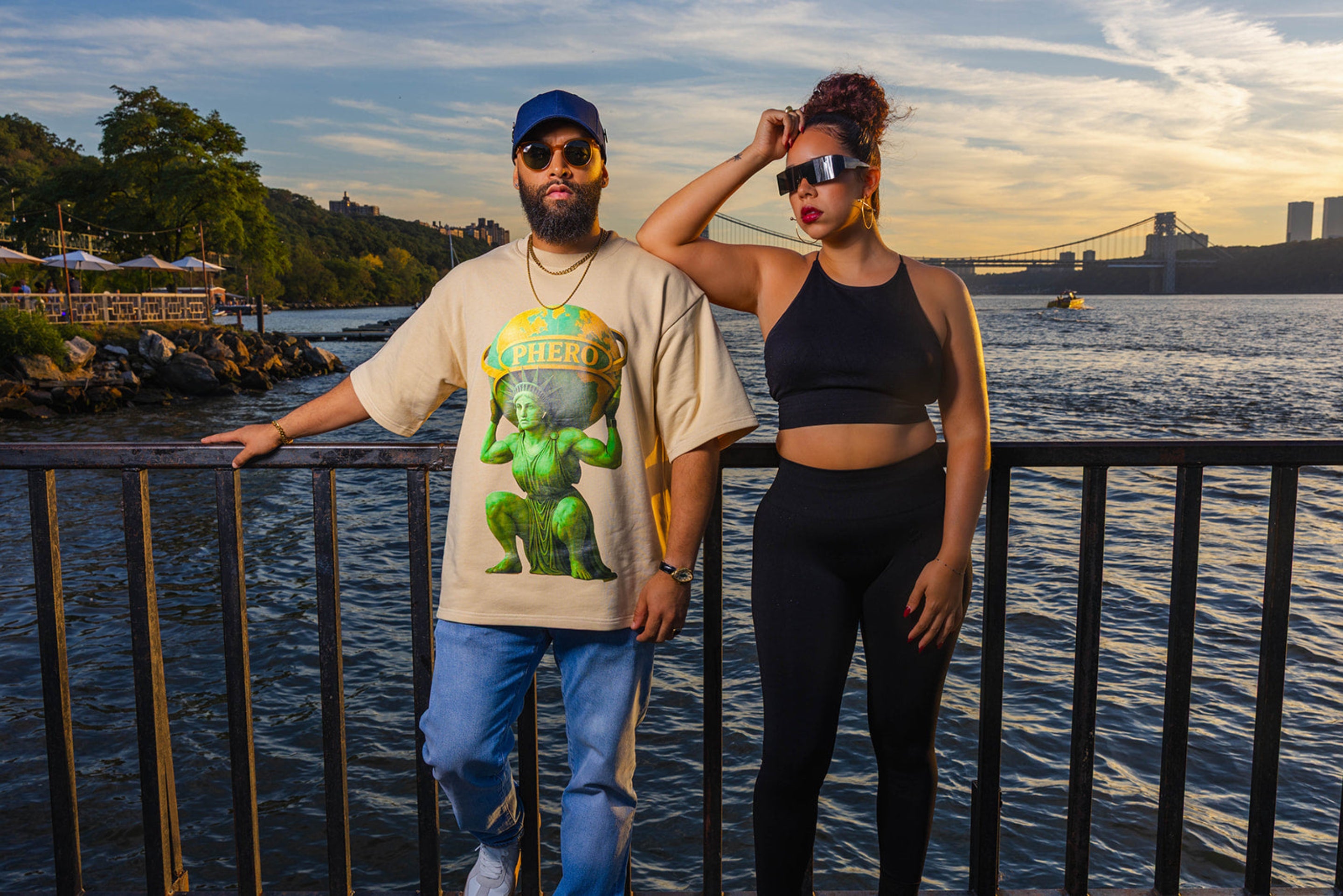Man and woman wearing PHERO MOVEMENT athleisure standing by a waterfront at sunset